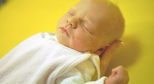 Neugeborenes wird von einer Hand getragen
